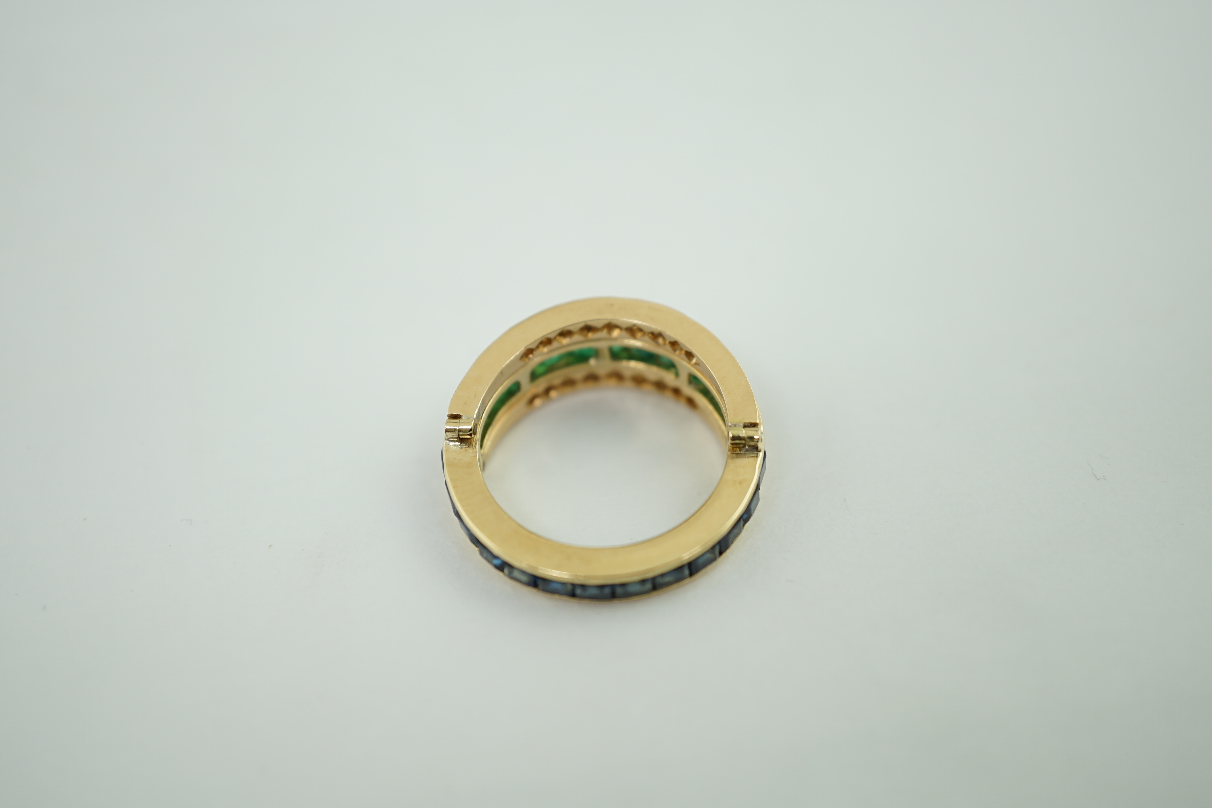 A recent gold, emerald, sapphire and diamond set triple band swivelling eternity ring